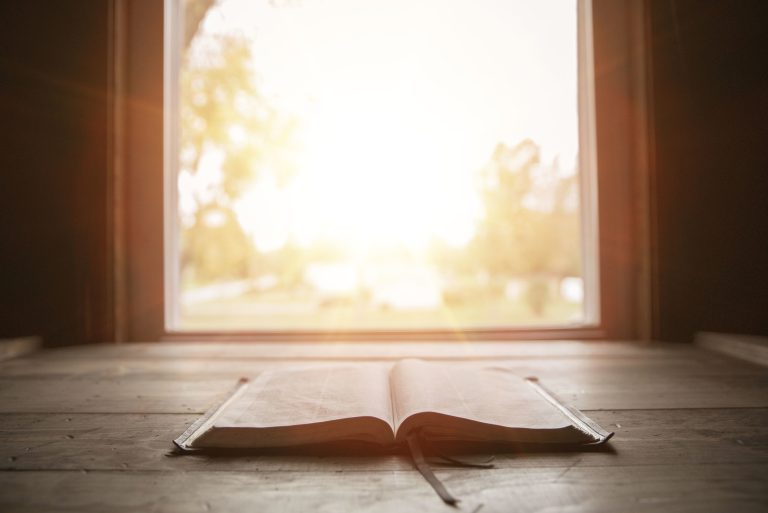 A close shot of holy bible on a wooden surface with the sun shining in the background (Photo: iStock - Wirestock)