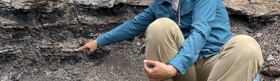 UW Professor Ellen Currano touches the Cretaceous/Paleogene (K-Pg) boundary in the Denver Basin. (Photo by Regan Dunn.)