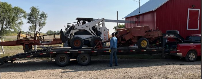 Twine baler and accumulator loaded on trailer by skidsteer for transport to Nebraska (Photo: Frank J Buchman)