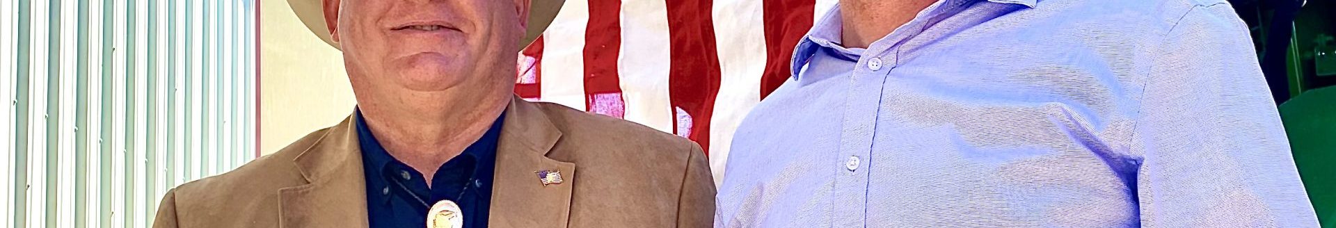 U.S. Reps. Glenn “GT" Thompson, R-PA, chairman of the House Agriculture Committee, left, and Tracey Mann, R-KS, pose for photos in front of a patriotic backdrop May 2, after the Kansas Food & Agriculture Listening Session in a farm shop north of Gypsum, Kansas (Photo by Tim Unruh.)