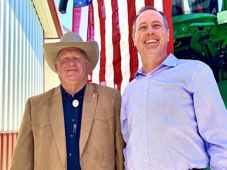 U.S. Reps. Glenn “GT" Thompson, R-PA, chairman of the House Agriculture Committee, left, and Tracey Mann, R-KS, pose for photos in front of a patriotic backdrop May 2, after the Kansas Food & Agriculture Listening Session in a farm shop north of Gypsum, Kansas (Photo by Tim Unruh.)