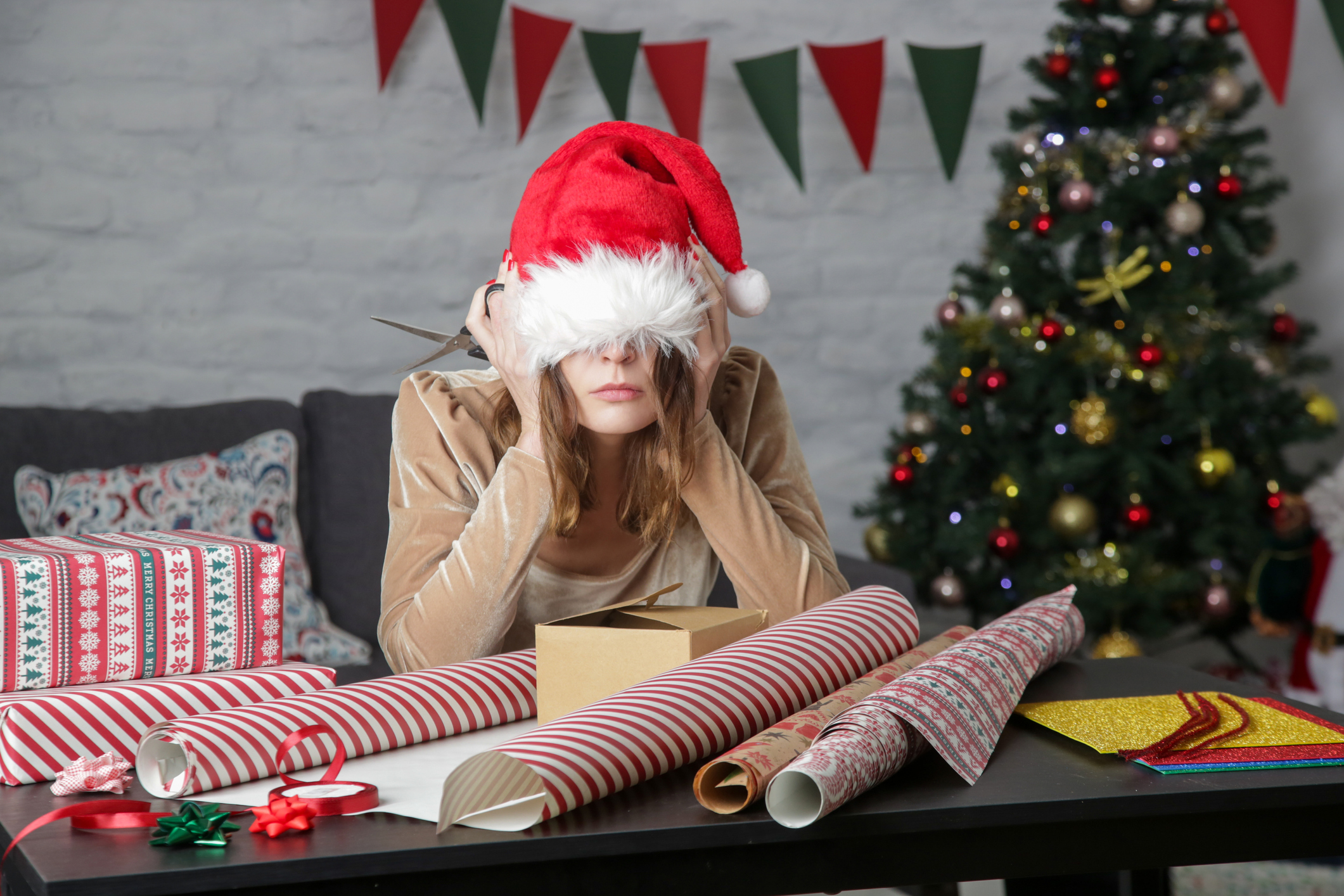 Depressed frustrated woman wrapping Christmas gift boxes, winter holiday stress concept (Photo: iStock - triocean)