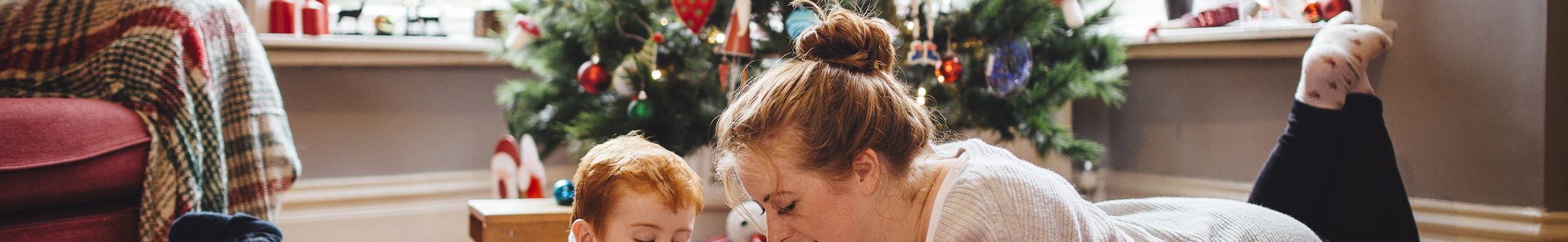 A young mother and her son are celebrating Christmas morning together, they are both lying on the floor and playing with newly opened toys together. (Photo: iStock - SolStock)