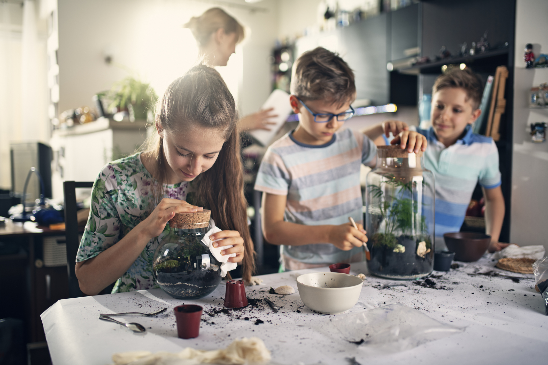 Kids having fun creating bottle gardens at home. They are potting little plants inside bottles to create miniature living eco-systems and beautiful home decoration. (Photo: iStock - Imgorthand)