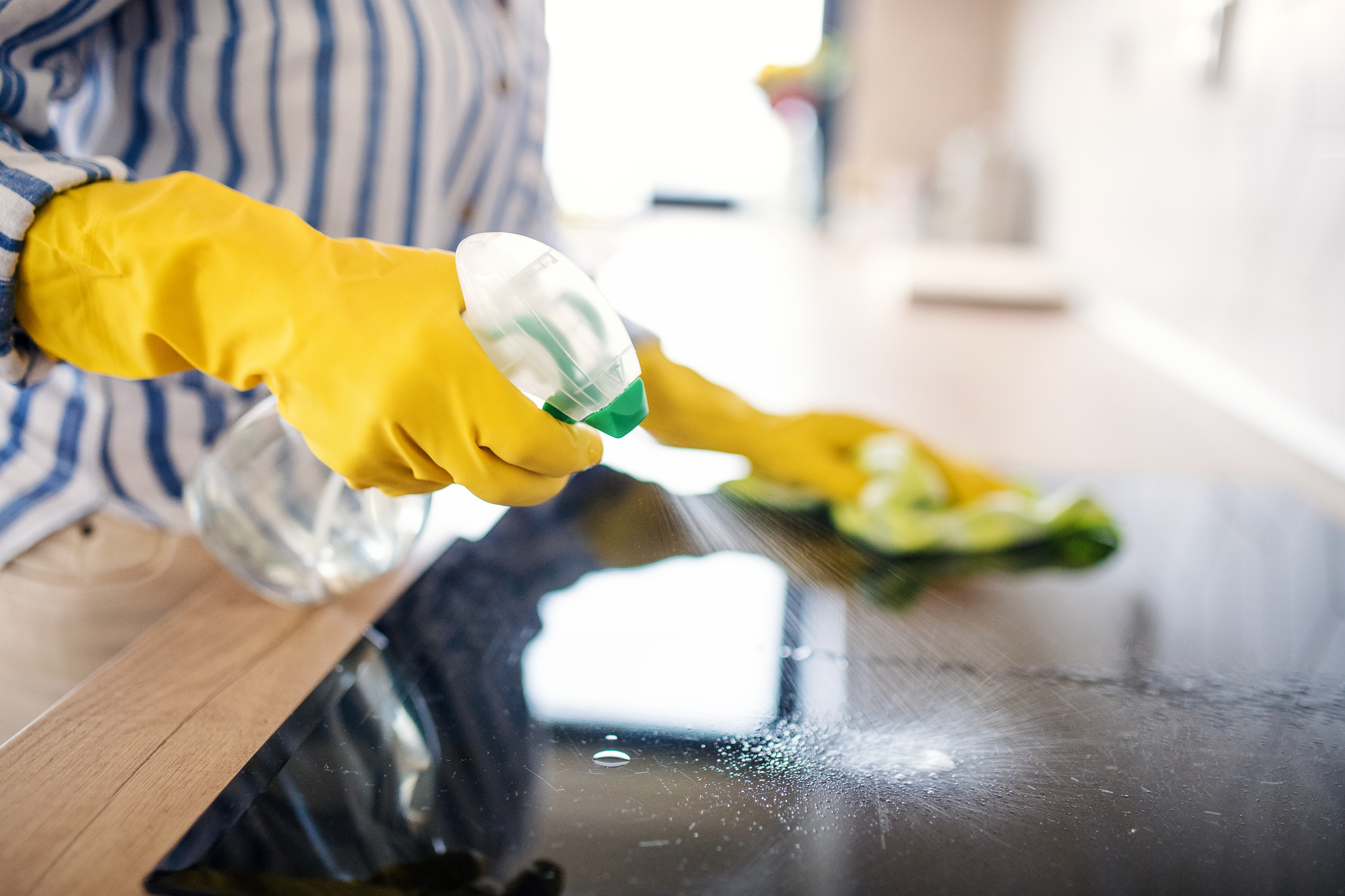 Woman cleaning kitchen counter indoors at home (Photo: iStock - Halfpoint)