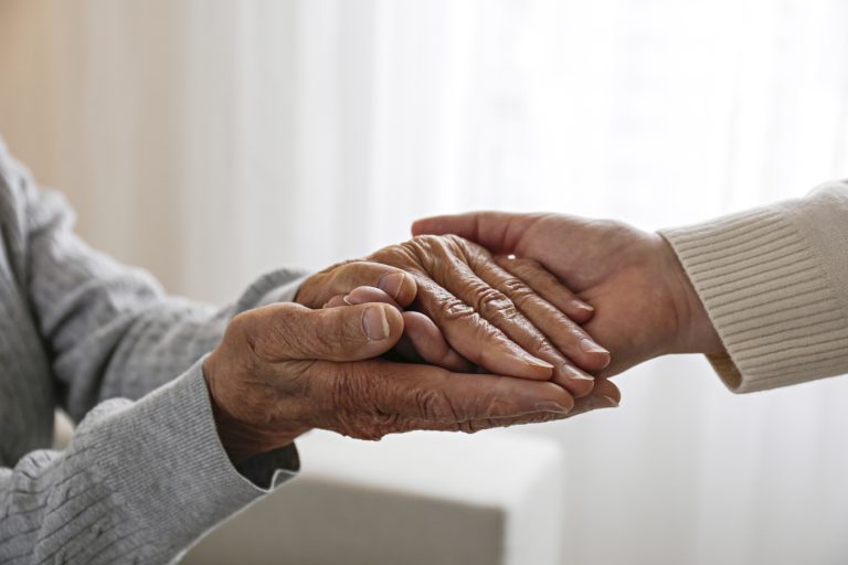 Mature female in elderly care facility gets help from hospital personnel nurse. Cropped shot of senior woman's hands with aged wrinkled skin and care giver. (Photo: iStock - Evrymmnt)