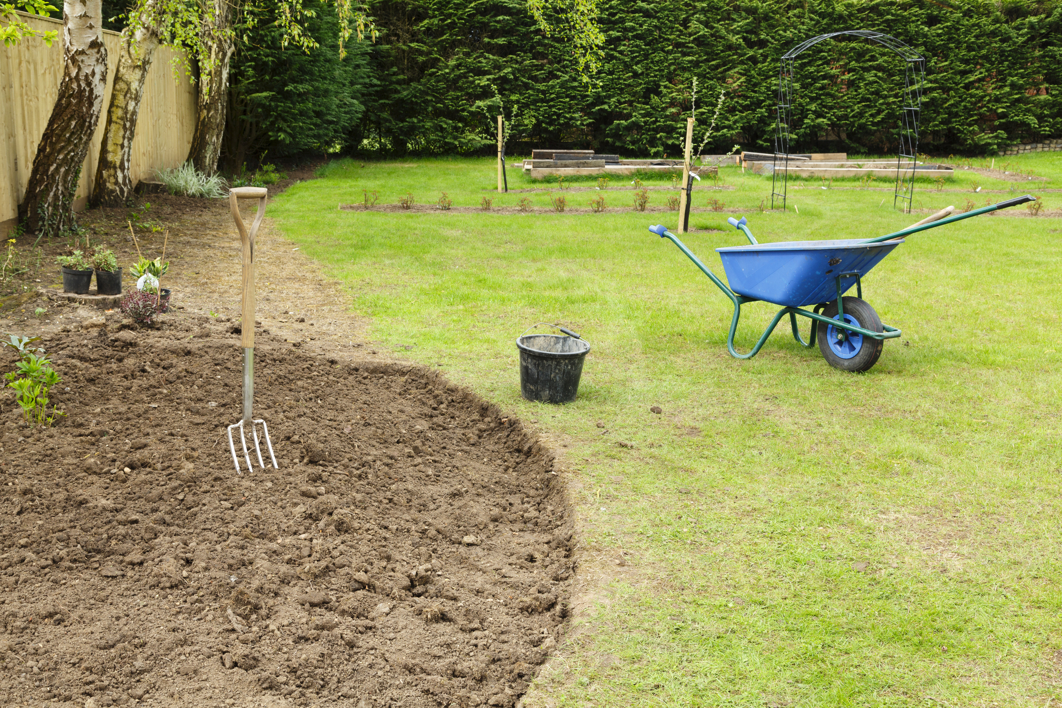 Preparing a freshly dug flower bed for planting in a garden with fork and wheelbarrow (Photo: iStock - PaulMaguire)