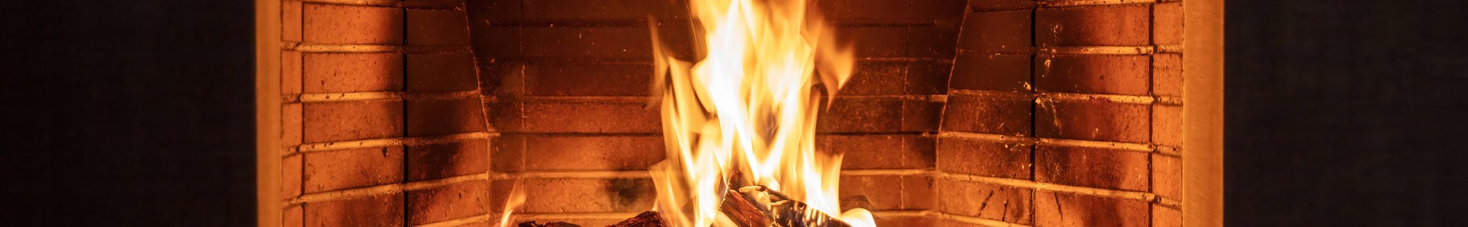 Fireplace burning firewood. Fire flames on wood logs, fireside bricks background. (Photo: iStock - Rawf8)