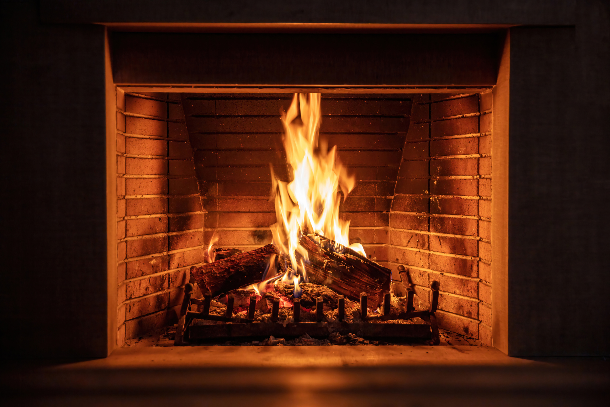 Fireplace burning firewood. Fire flames on wood logs, fireside bricks background. (Photo: iStock - Rawf8)