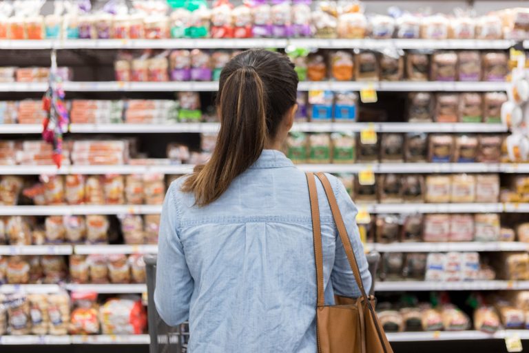 A woman stands with a shopping cart in front of a shelf full of food in the bread aisle of a grocery store. (Photo: iStock - SDI Productions)