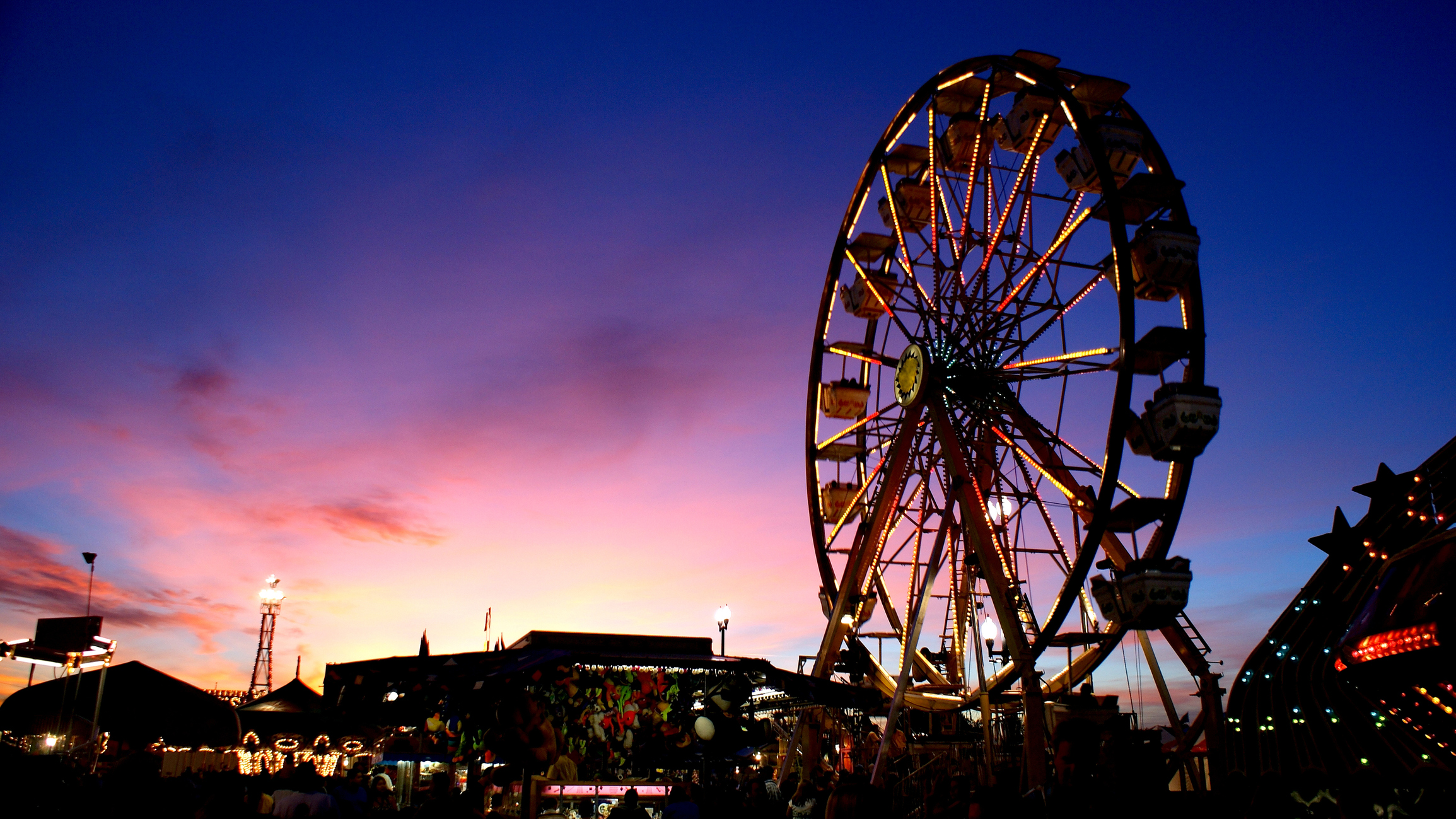 State Fairground Farris Wheel Ride with Multicolored Lights Spinning at Sunset along with Carnival Games, Carnival Rides in image. (Photo: iStock - Clayton Piatt)