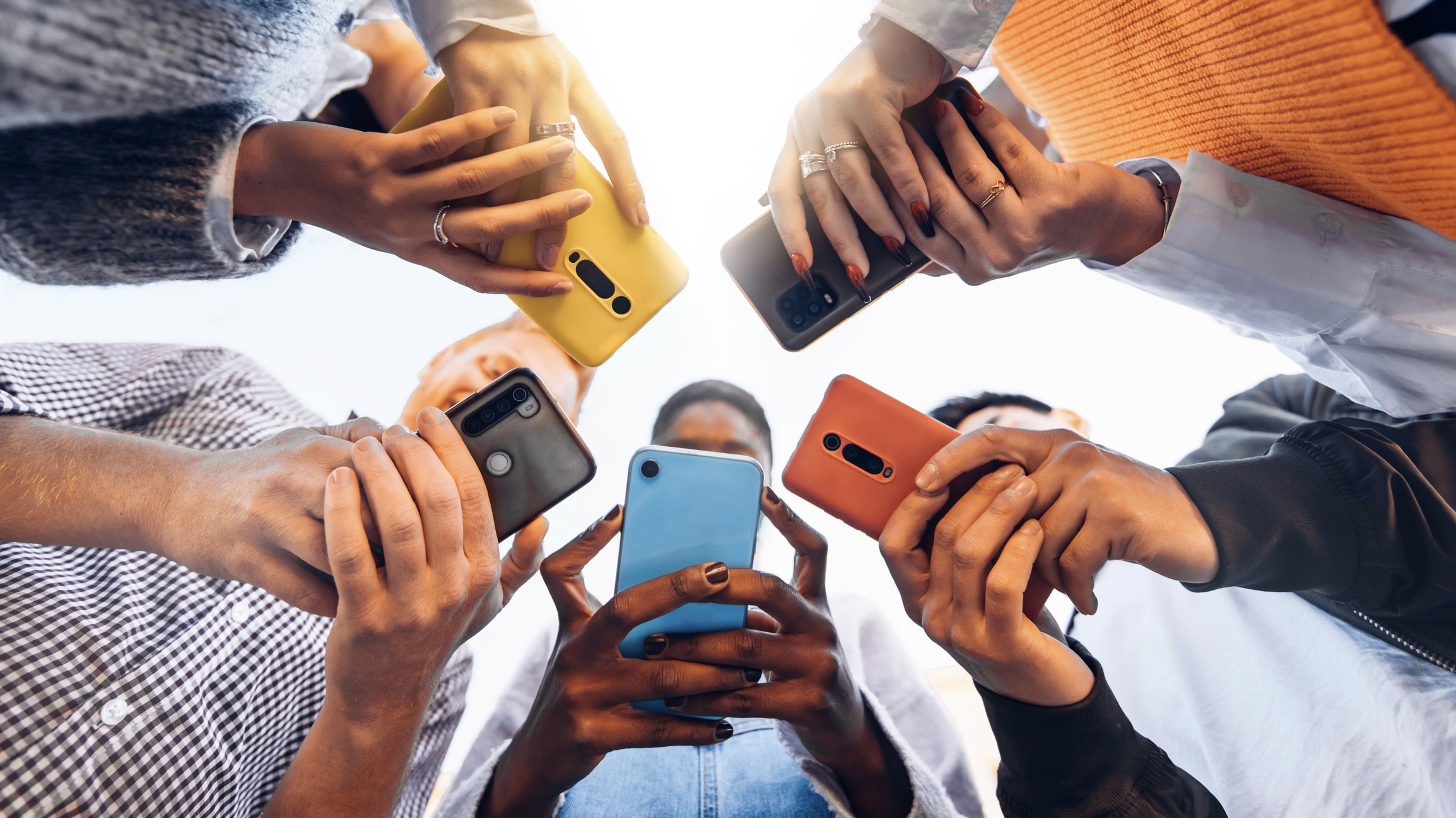 Teens in circle holding smart mobile phones. (Photo: iStock - Kar-Tr)