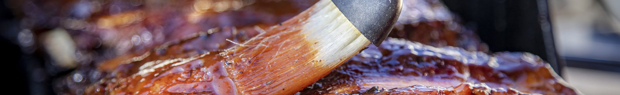 Beef ribs being basted with bbq sauce on a grill with a basting brush (Photo: iStock - Frank Armstrong)