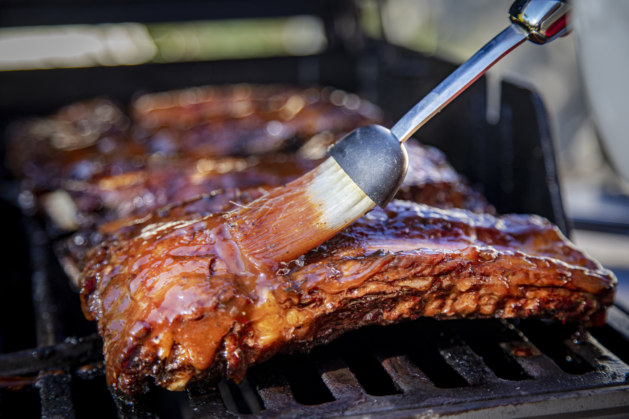Beef ribs being basted with bbq sauce on a grill with a basting brush (Photo: iStock - Frank Armstrong)