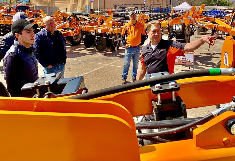 Farmada President Daniel Rauchholz, right, points out a feature on his Elixir 64 high speed, low disturbance fertilizer applicator, to Ukrainian agribusinessmen Sergii Kovalchuk, left, and Oleksii Khvorostianyi, during their March 21 visit to the Mid America Farm Expo in Salina, Kansas. Looking on at back right is Darren Zerr, Farmada sales manager. (Photo by Tim Unruh.)