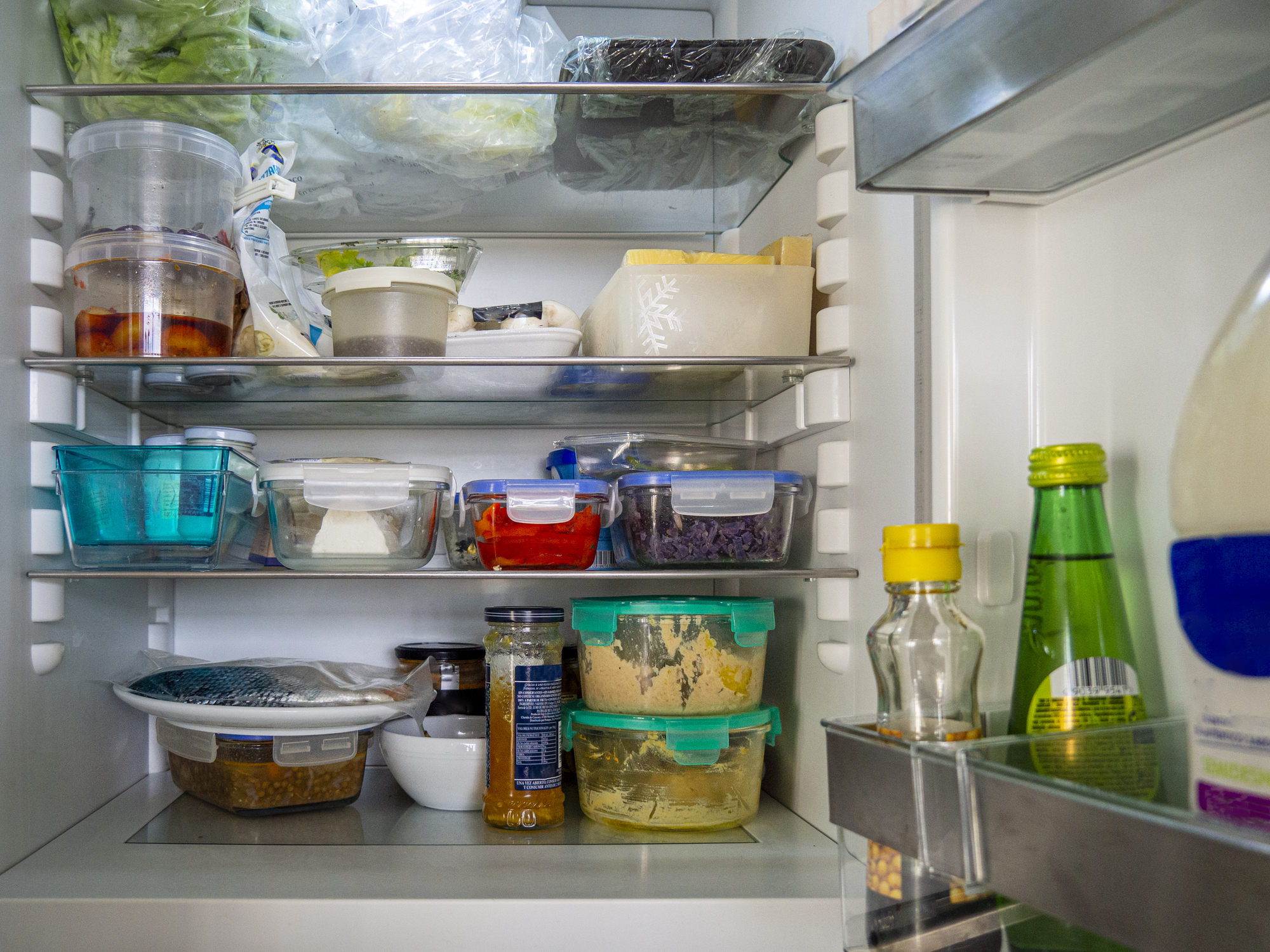 Open fridge with food leftovers and meal plan in glass containers. Domestic refrigerator for healthy eating. Leftover food, yogurt, cheese and other groceries. (Photo: iStock - Olga PS)