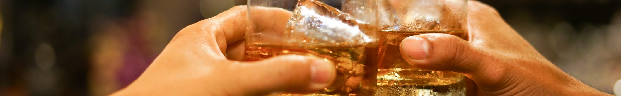 Two men clinking glasses of whiskey drink alcohol beverage together at counter in the pub (Photo: iStock - krisanapong detraphiphat)