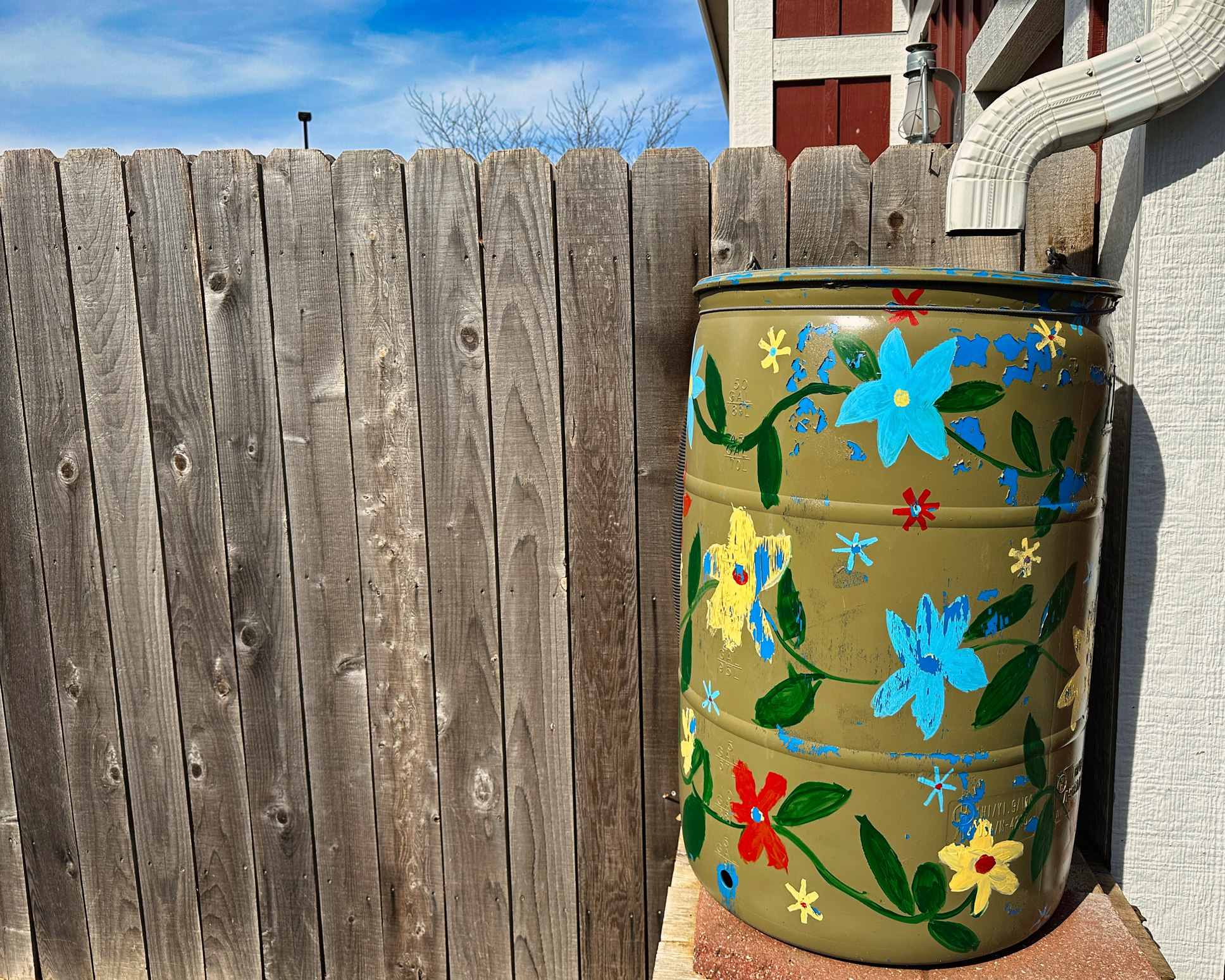Painted Flowers on Green Rain Barrel by Wood Fence (Photo: iStock - Matthew Fowler)