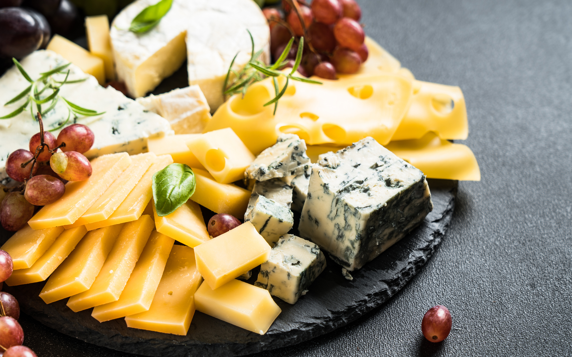 Cheese platter with craft cheese assortment and grape on slate board. (Photo: iStock - Nadiia Borovenko)