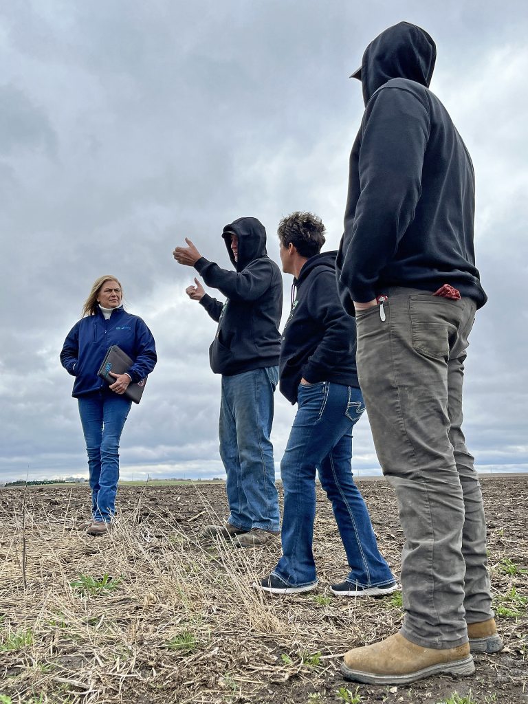 Iowa NRCS District Conservationist Lissa Tschirgi (left) talks to the Rooney family (Jeff, Karla and Justin) one of their no-till fields. (Photo by Carrie Chlebanowski, NRCS.)