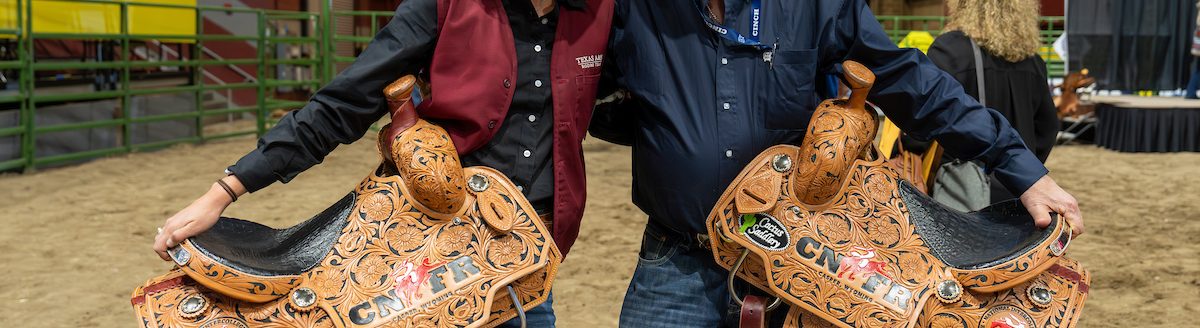 Madalyn Richards ’25, of Hereford, collects her champion saddles with Aggie Rodeo coach Al Wagner, Ph.D., after being named the 2024 Breakaway Roping Champion and earning the 2024 Women’s All-Around title during College National Finals Rodeo in Casper, Wyoming. (Michael Miller/Texas A&M AgriLife)