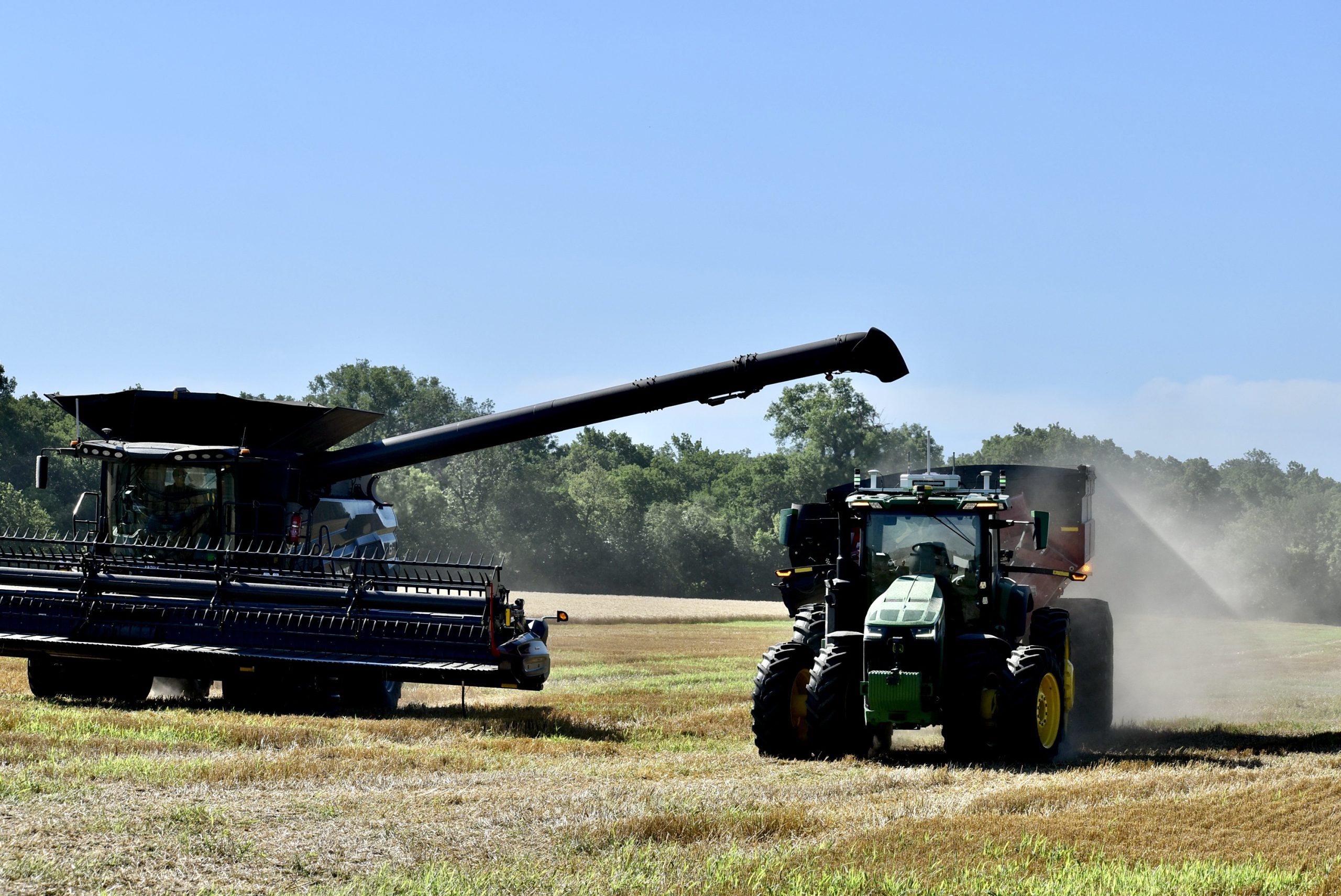 An autonomous tractor/grain cart, controlled by a computer program, pulls alongside a combine that needs to be unloaded in a wheat field during a demonstration last month at AGCO Tech Day southeast of Salina, Kansas. The equipment is designed to fill labor shortages, save time and add to the bottom lines of farmers. (Photo by Tim Unruh.)