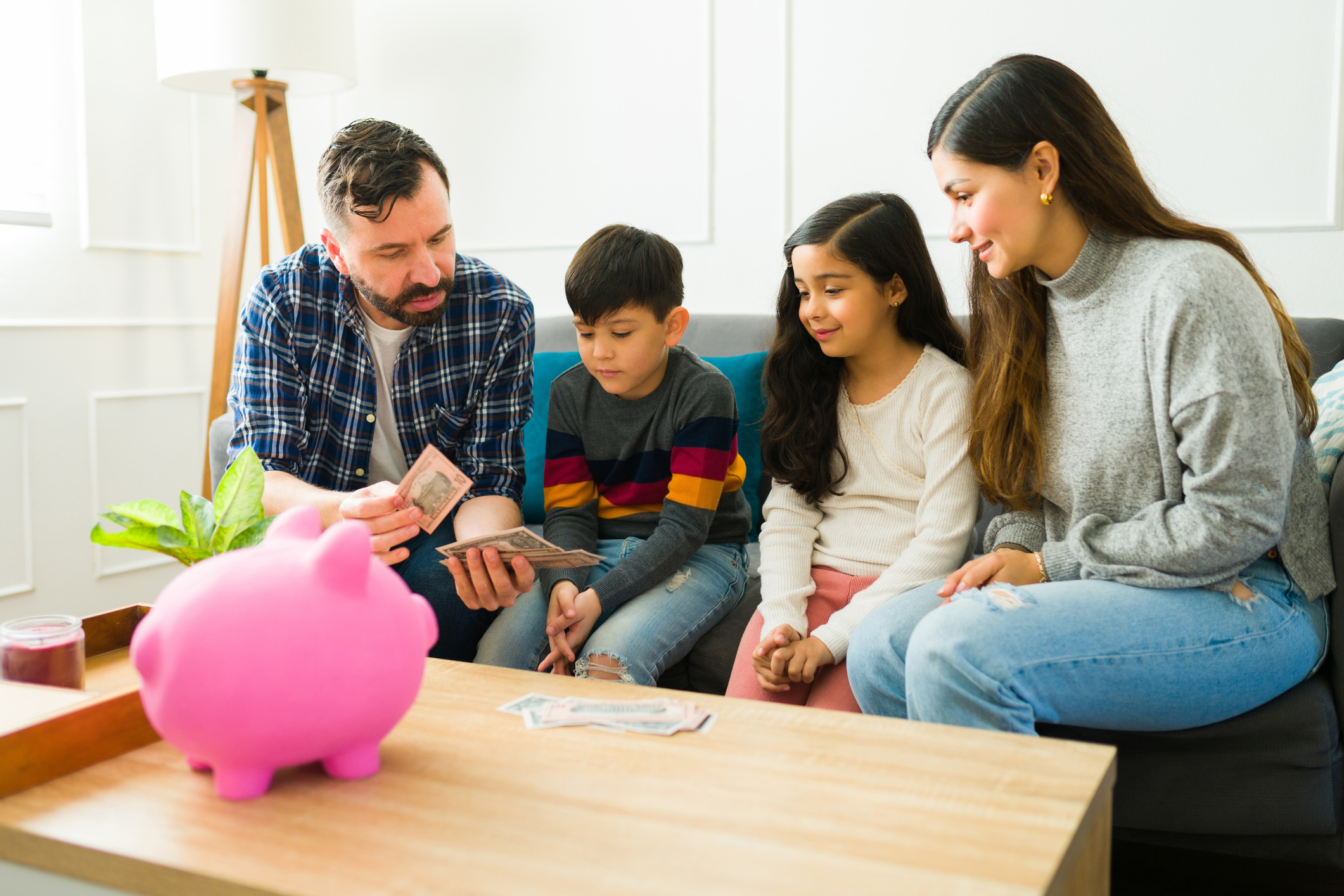 Caring parents teaching financial education to their children while counting money together to put in the piggy bank (Photo: iStock - Antonio_Diaz)