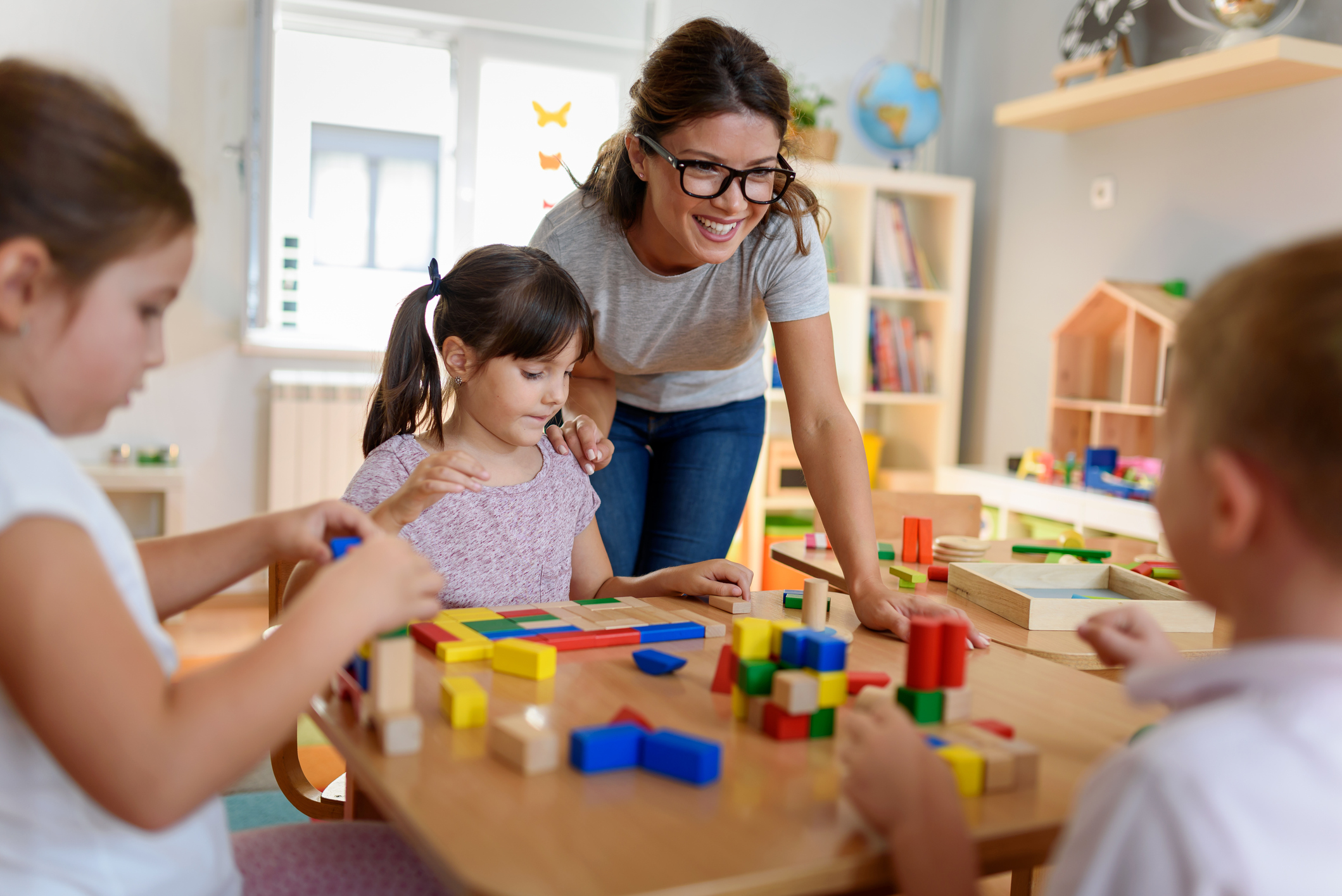 Preschool teacher with children playing with colorful wooden didactic toys at kindergarten (Photo: iStock - Lordn)