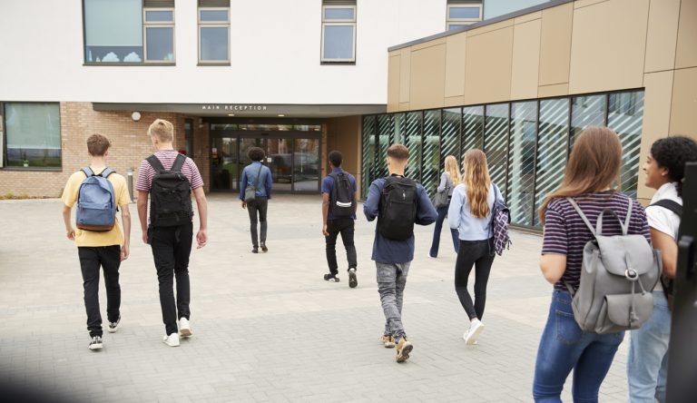 Rear view of high school students walking into school building (Photo: iStock - monkeybusinessimages)