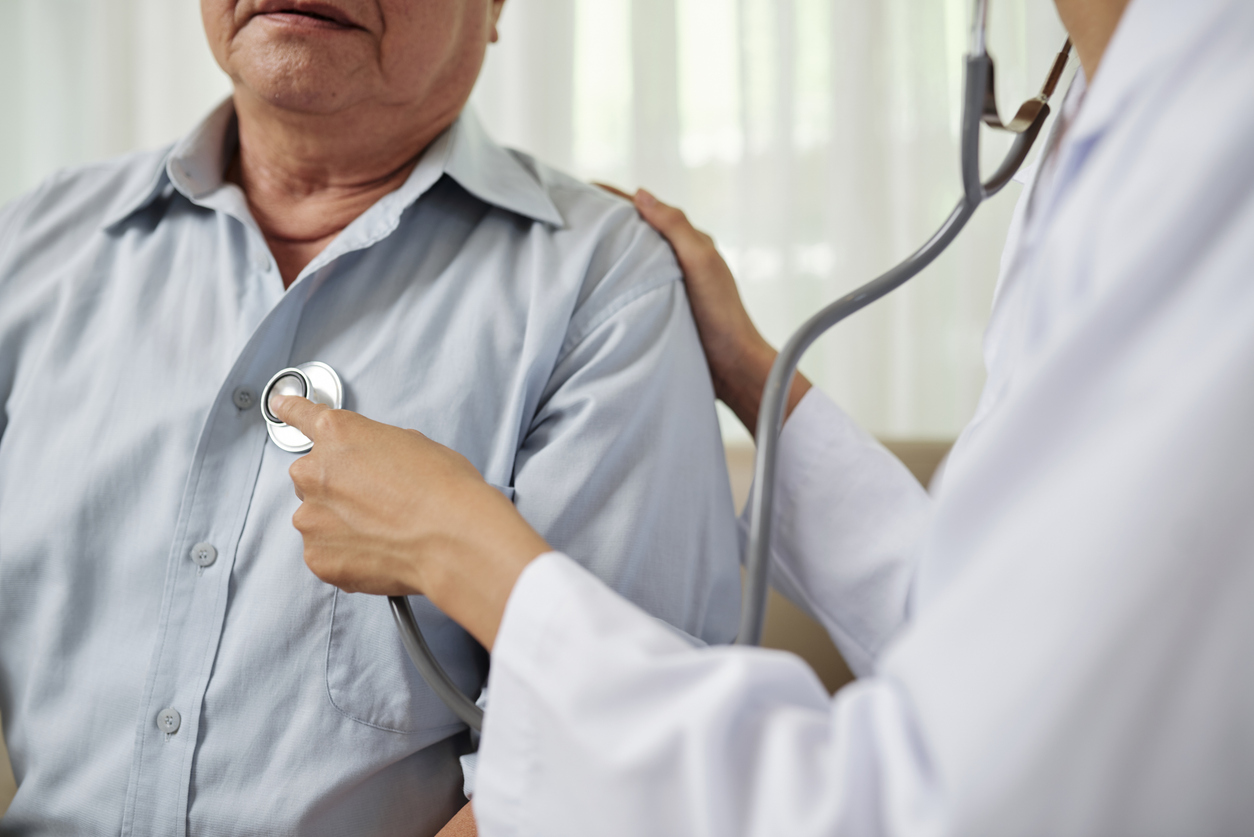 Close-up of female doctor in white coat listening to breathe of senior man during his visit at hospital (Photo: iStock - DragonImages)