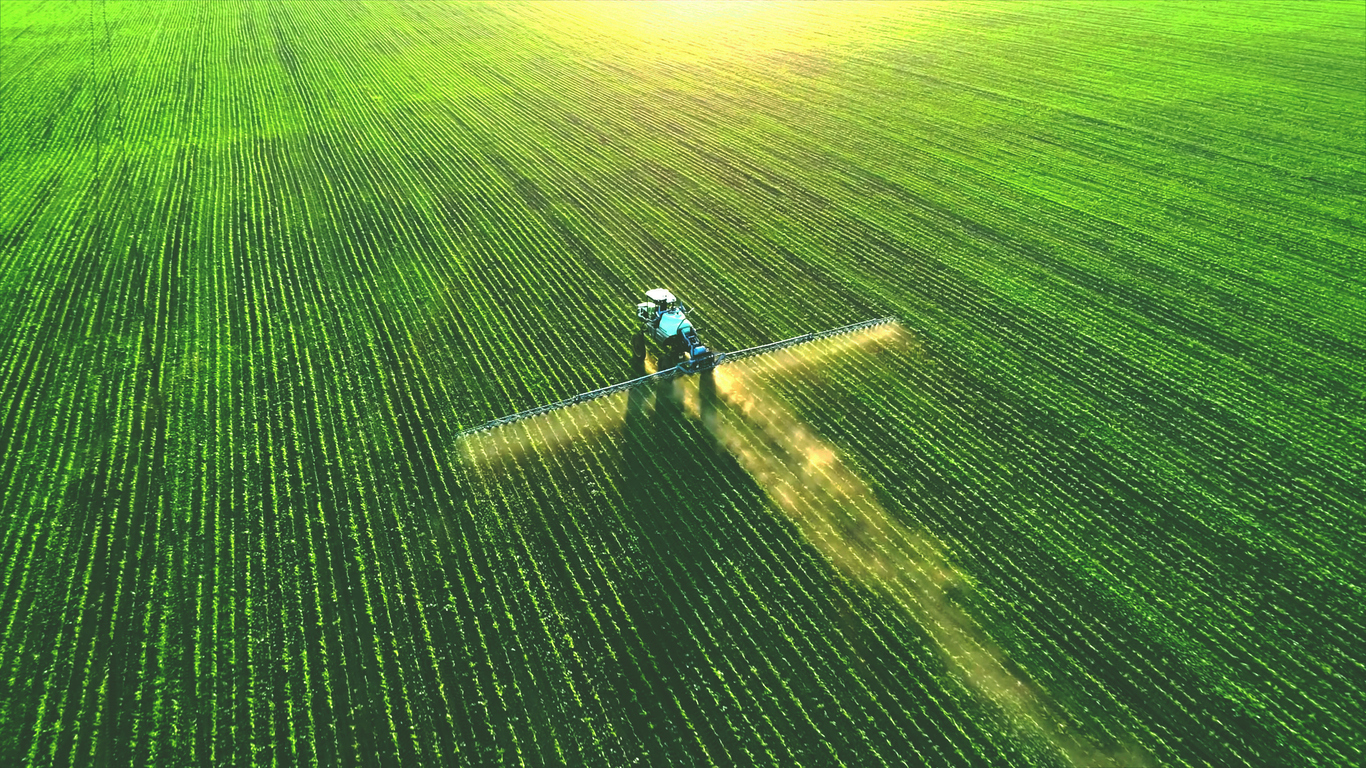 Tractor spray fertilizer on green field. (Photo: iStock - moiseXVII)