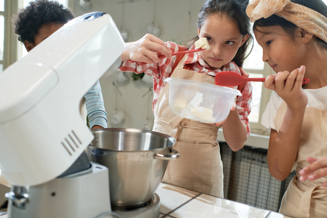 Group of children adding ingredients in the bowl and making cream for cake together in team during cooking lesson (Photo: iStock - AnnaStills)