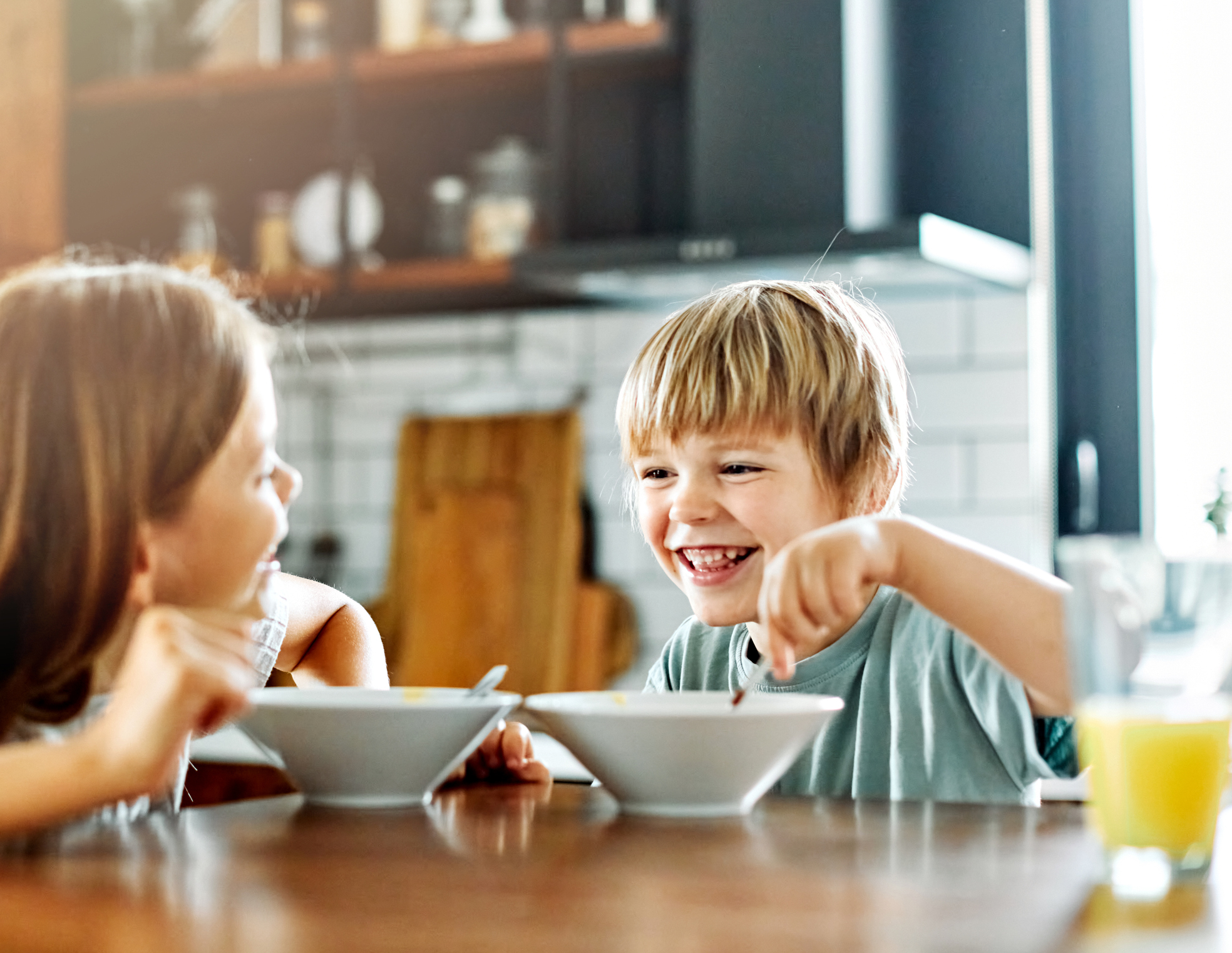 Portrait of brother and sister having fun together eating breakfast strawberries in kitchen (Photo: iStock - Paperkites)