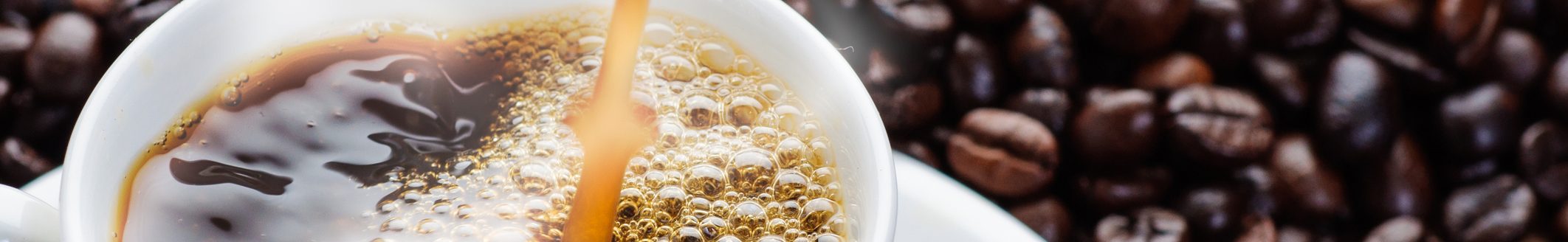 coffee pouring to cup surrounded by coffee beans (Photo: iStock - iWichy)