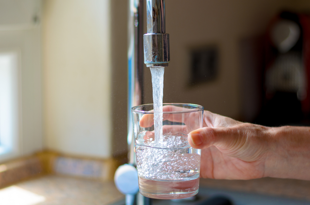 Woman filling a glass of water from a stainless steel or chrome tap or faucet (Photo: iStock - mheim3011)