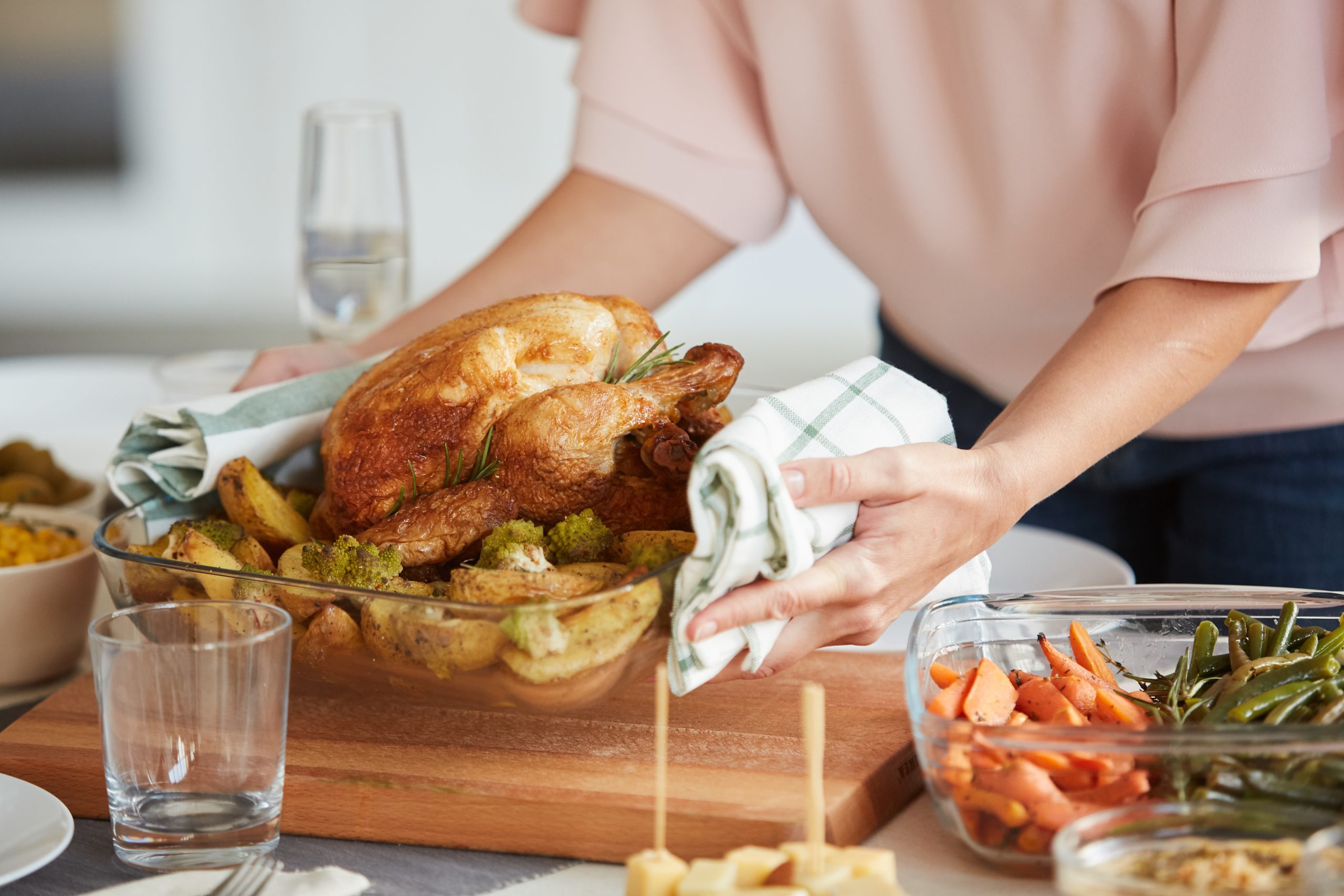 Close-up of woman putting the dish with roast turkey and potatoes on the dining table for Thanksgiving Day (Photo: Adobe Stock │ #295108810 - AnnaStills)