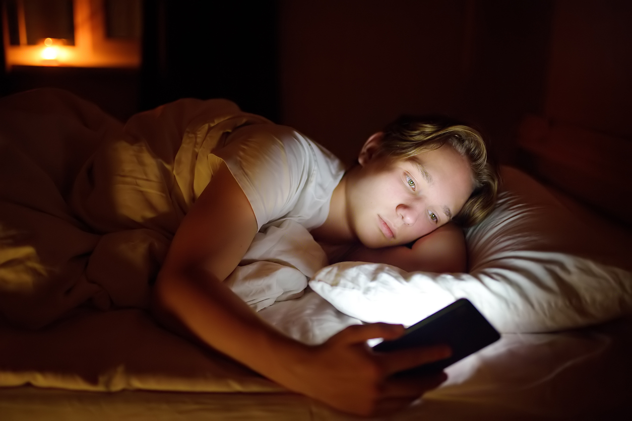 Teenager boy chatting by phone, writing in blog or reading social networks instead of sleeping. (Photo: iStock - SbytovaMN)