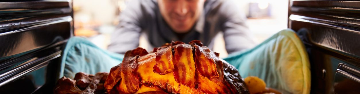 Man Taking Roast Turkey Out Of The Oven. (Photo: iStock - monkeybusinessimages)