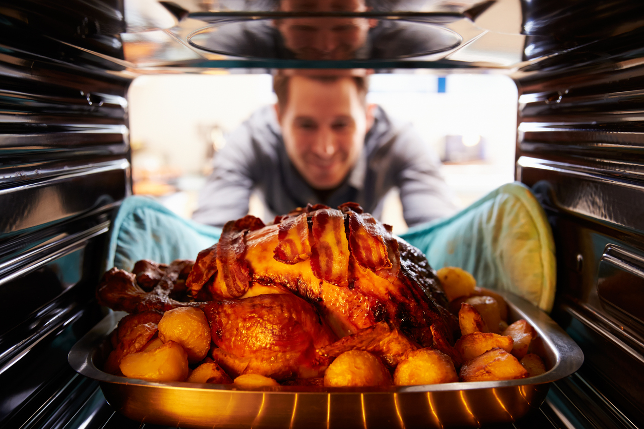 Man Taking Roast Turkey Out Of The Oven. (Photo: iStock - monkeybusinessimages)