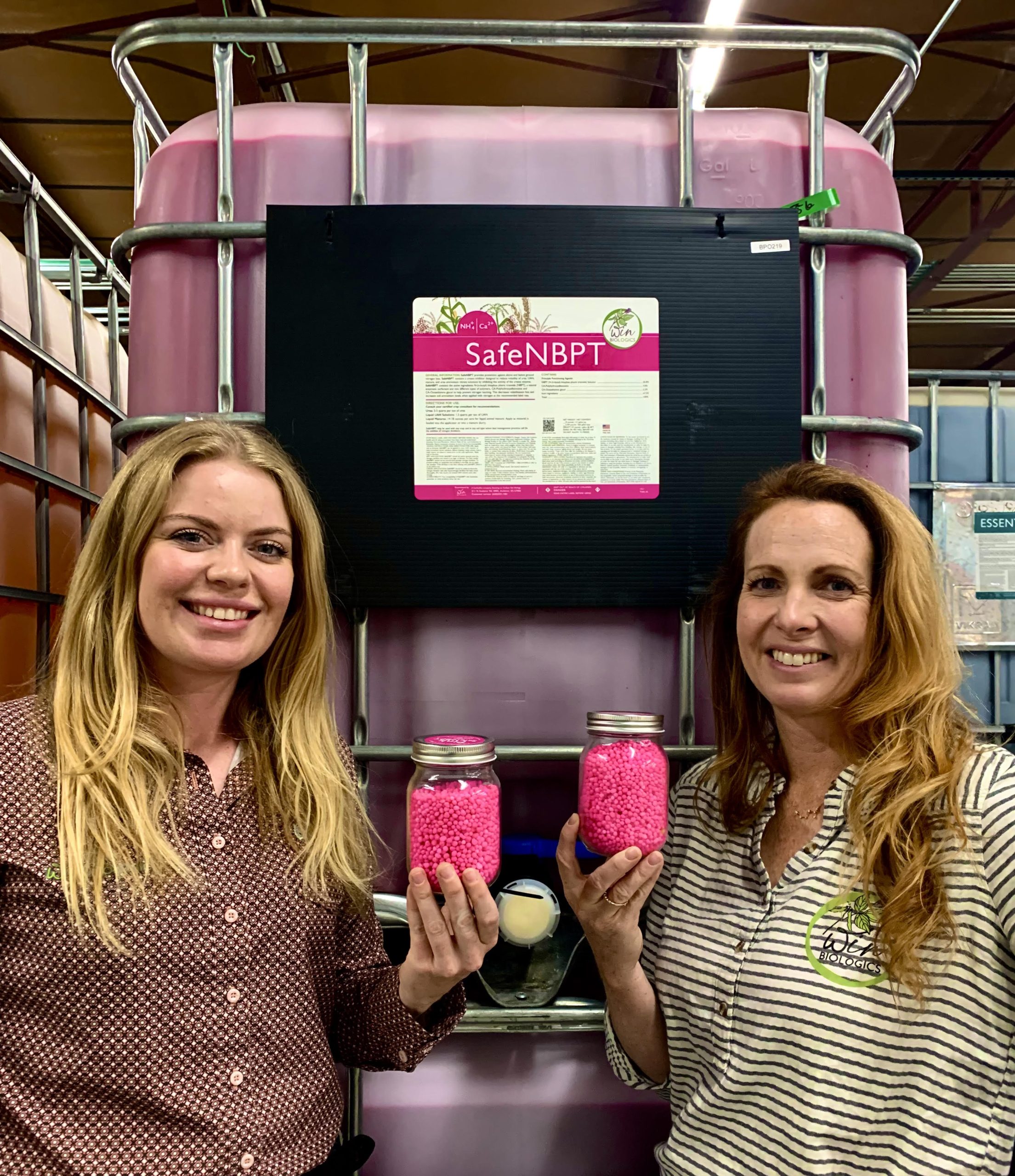 Win Biologics sales representative Raeann Magill, left, and company owner Carolyn Wingate pose with the hot pink urea they sell to farmers. (Journal photo by Tim Unruh.)