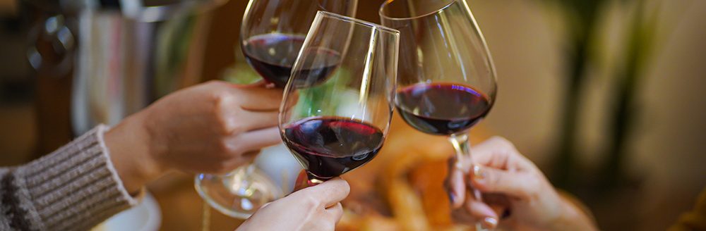 Friends cheering drinking red wine celebrating Christmas or New Year party. (Photo: Adobe Stock │ #602848856 - Charlie's)