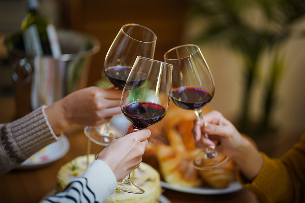 Friends cheering drinking red wine celebrating Christmas or New Year party. (Photo: Adobe Stock │ #602848856 - Charlie's)