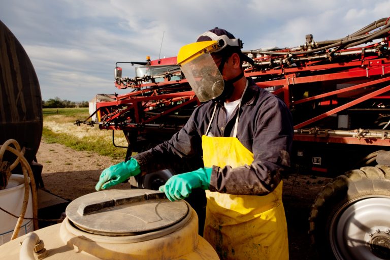 Filling a high clearance sprayer with chemical and water with proper safety equipment. (Photo: iStock - leaf)
