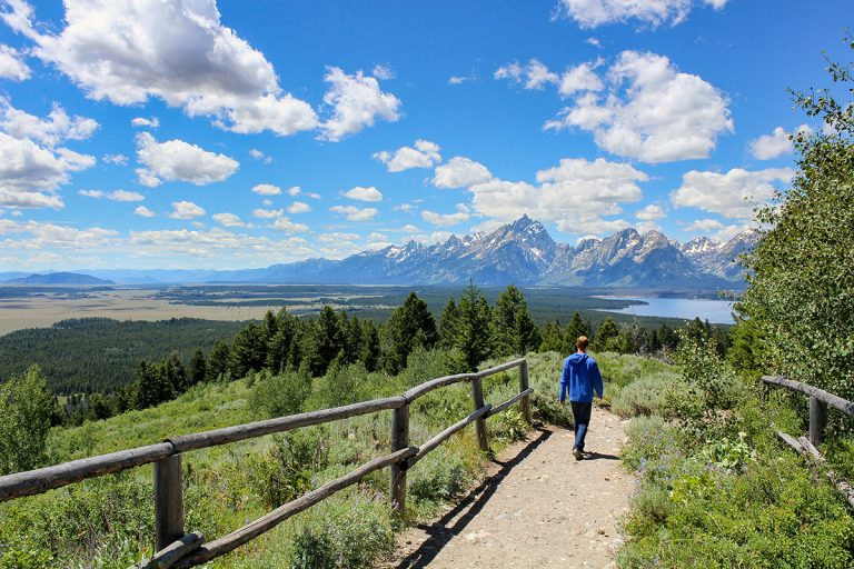 Boy hiking with Jackson Lake and Grand Teton Mountain in distance. (Photo: Adobe Stock │ #177778510 - Jeremy)
