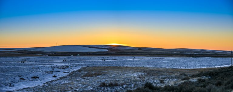 Vibrant golden-red sunset painted the horizon of the farmland in heavy winter, the sun has set below the hills, night has begun to take over, but the light from the sun has not completely faded yet, giving the land it's most romantic hour, with the snowfield reflecting the blue tone of the darken sky. Photo taken @ semi-desert stretch of eastern Washington by I-90 Lumaca Photo MyCameraDiary.com