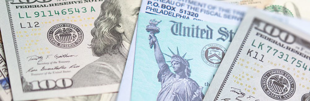 United States IRS check and envelope resting on money. (Adobe Stock │ #402728861 - Andy Dean)