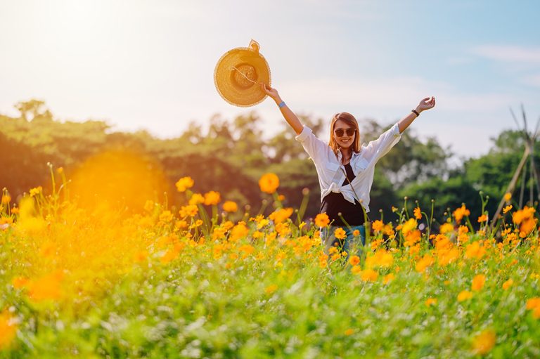 Young woman in a beautiful blooming flower field. (Adobe Stock │ #402092937 - Hide_Studio)