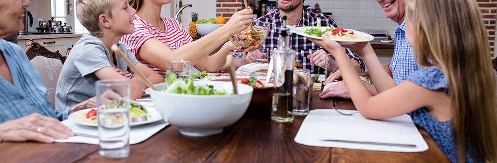 Woman serving food to her family in the kitchen. (Adobe Stock │ #106850789 - WavebreakmediaMicro)
