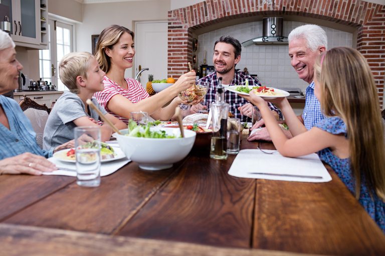 Woman serving food to her family in the kitchen. (Adobe Stock │ #106850789 - WavebreakmediaMicro)