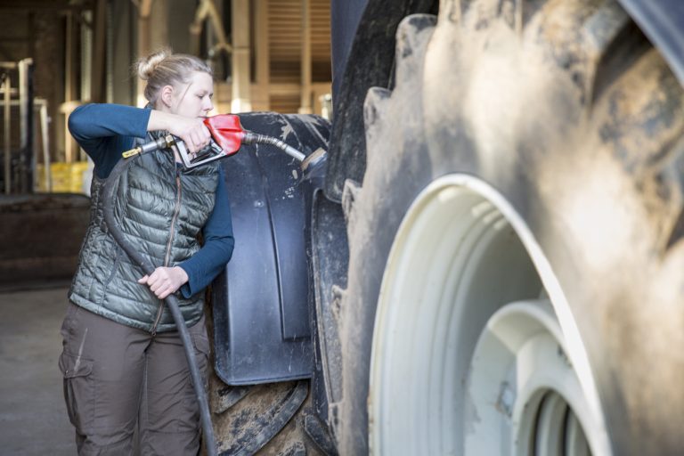 Female farmer refueling a tractor. (iStock │ #1181480737 - fotografixx)